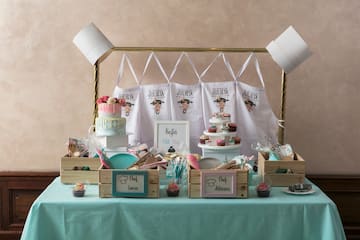 Kids' chef party table with cake, cupcakes, custom aprons, and individual baking kits.