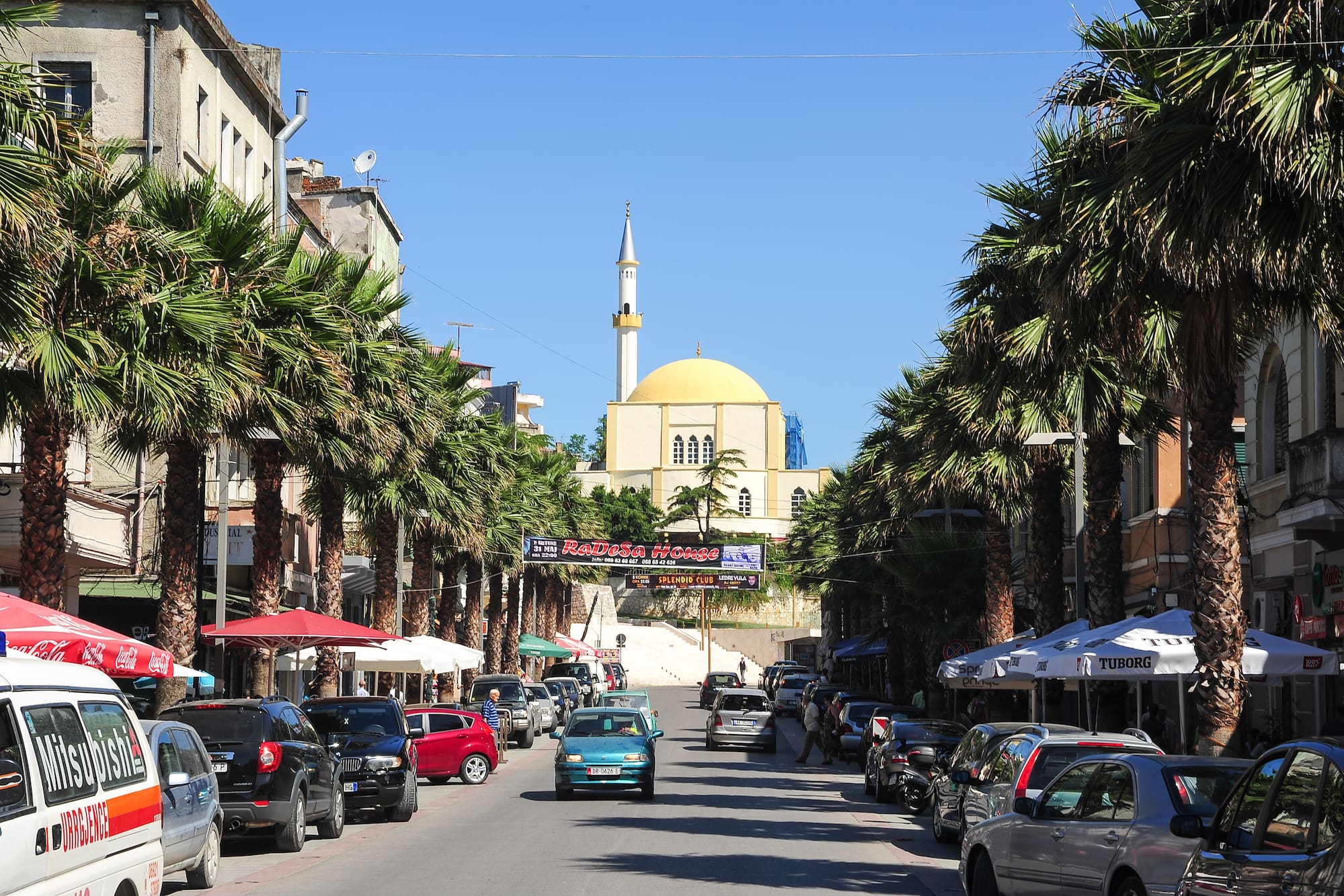 a street with cars and palm trees