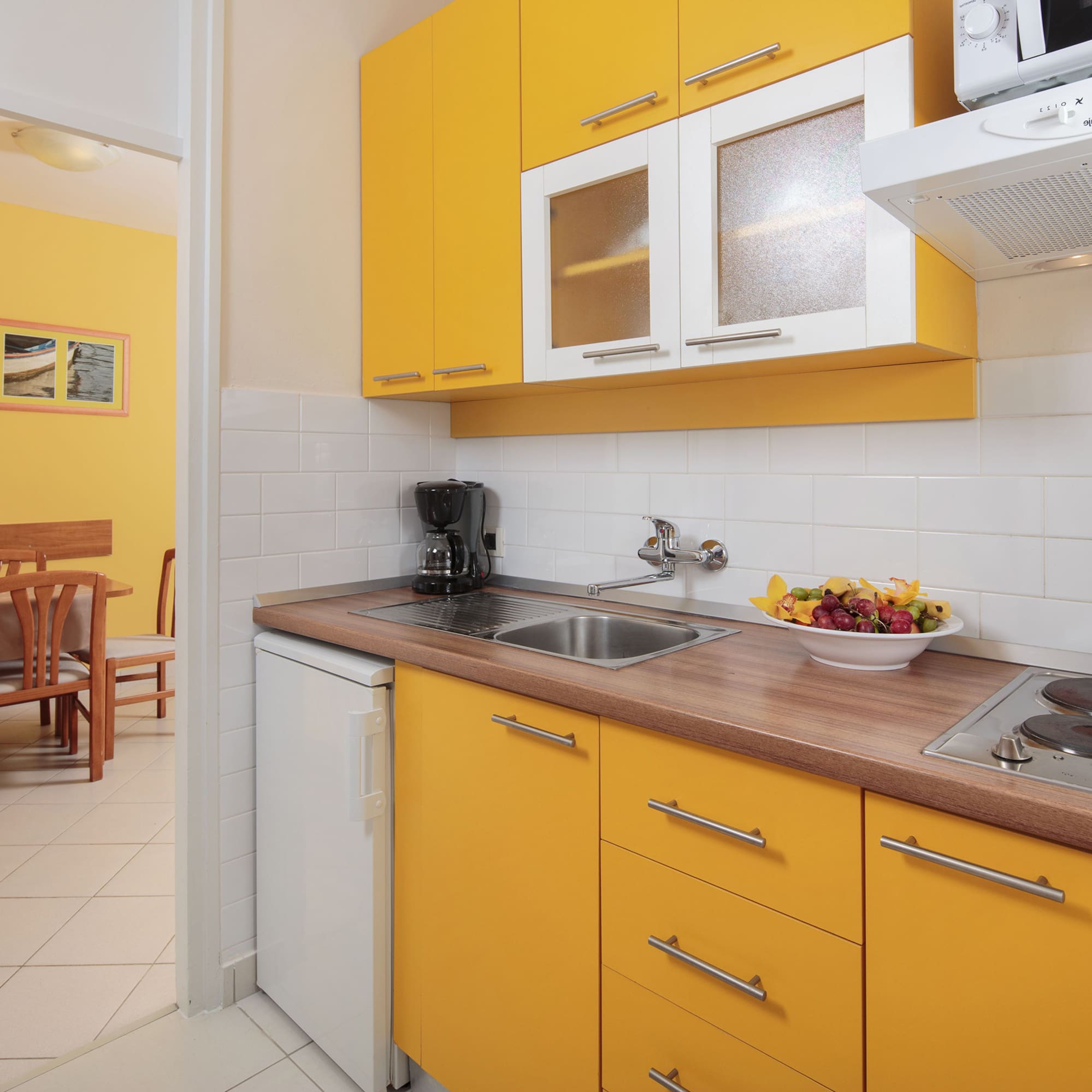 a kitchen with yellow cabinets and a white tile floor