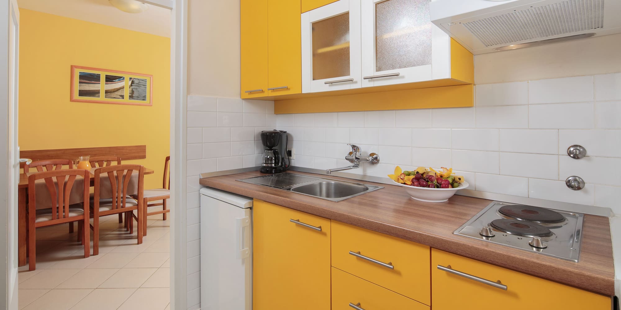 a kitchen with yellow cabinets and a white tile floor