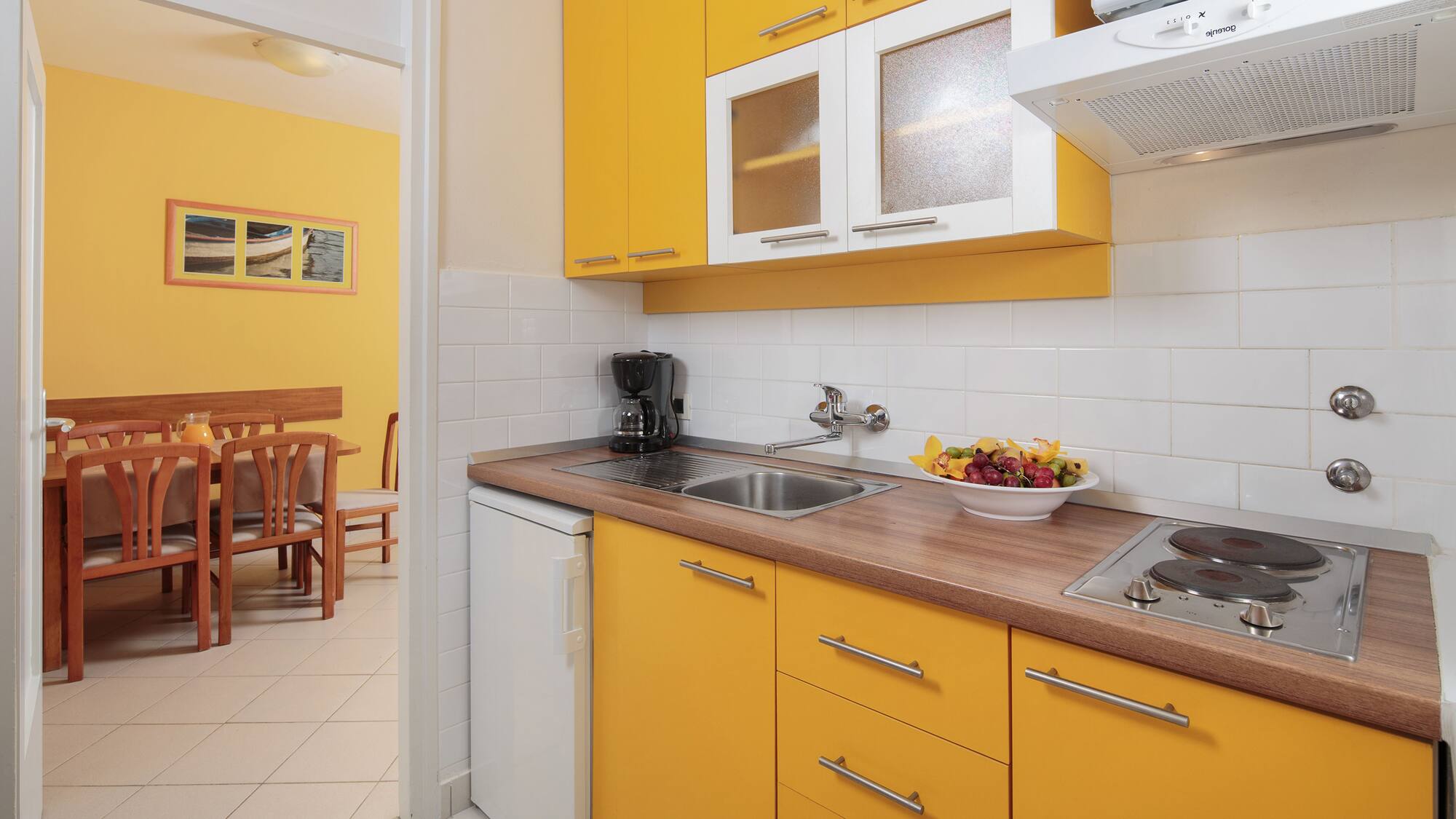 a kitchen with yellow cabinets and a white tile floor