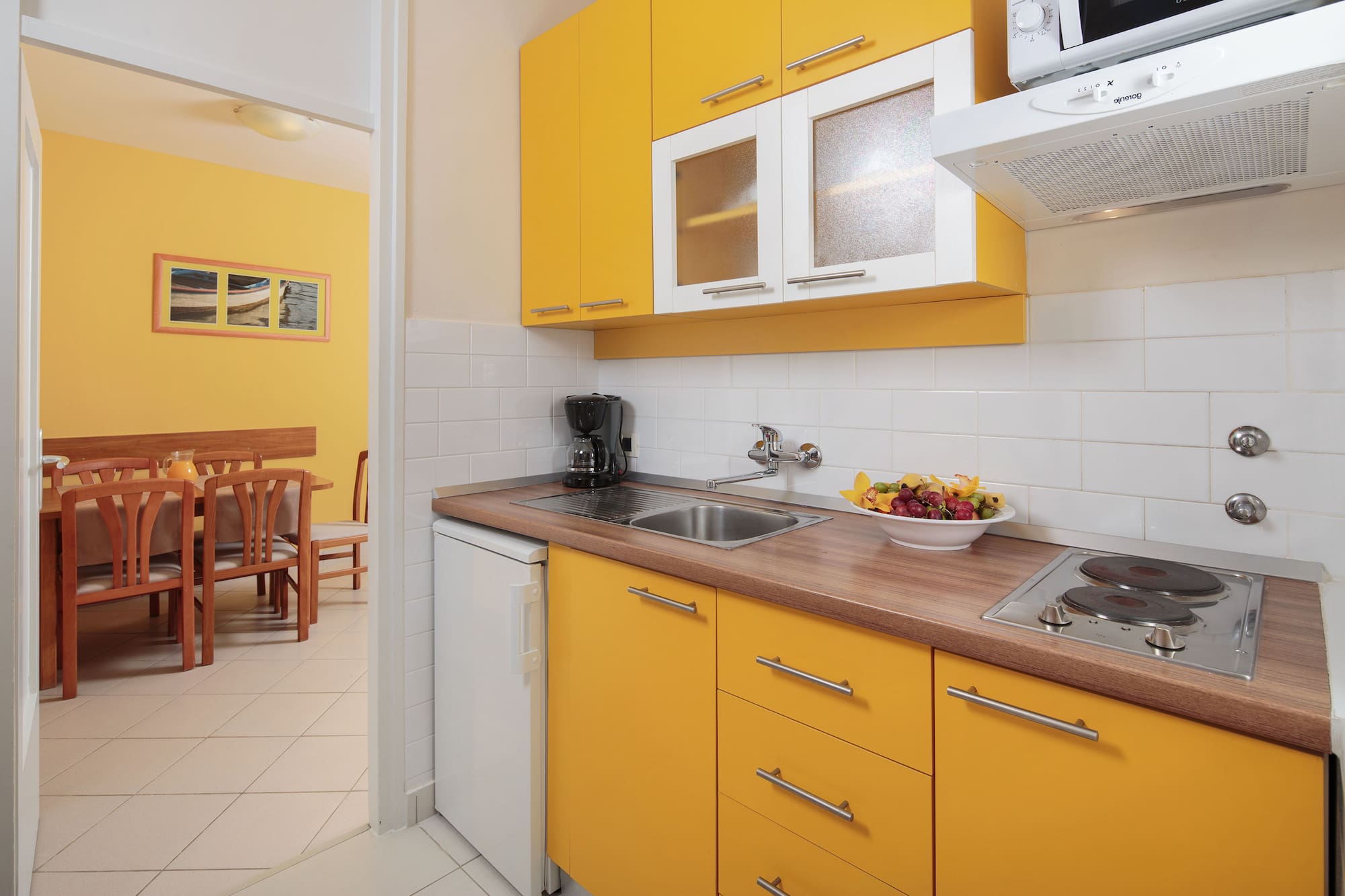 a kitchen with yellow cabinets and a white tile floor