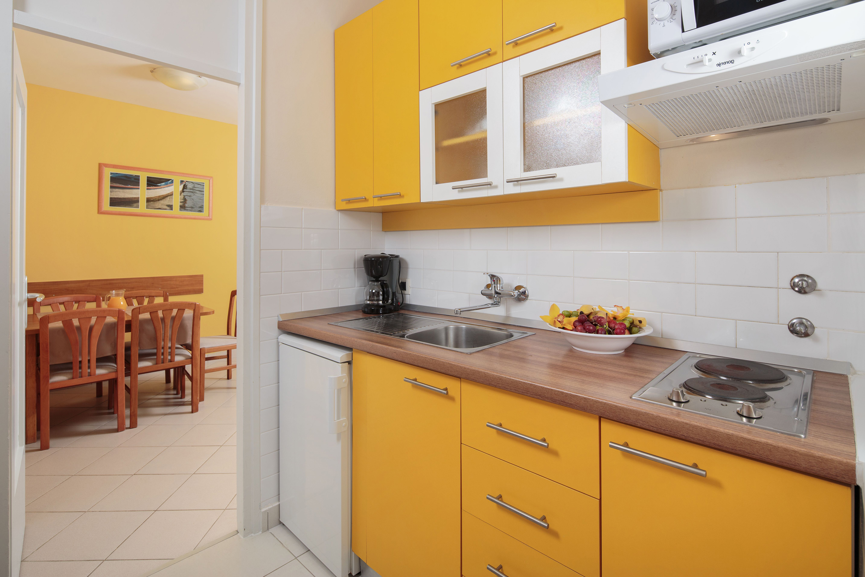 a kitchen with yellow cabinets and a white tile floor
