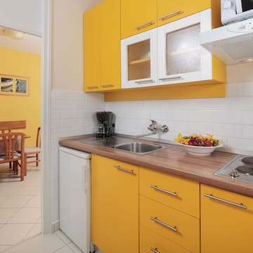 a kitchen with yellow cabinets and a white tile floor