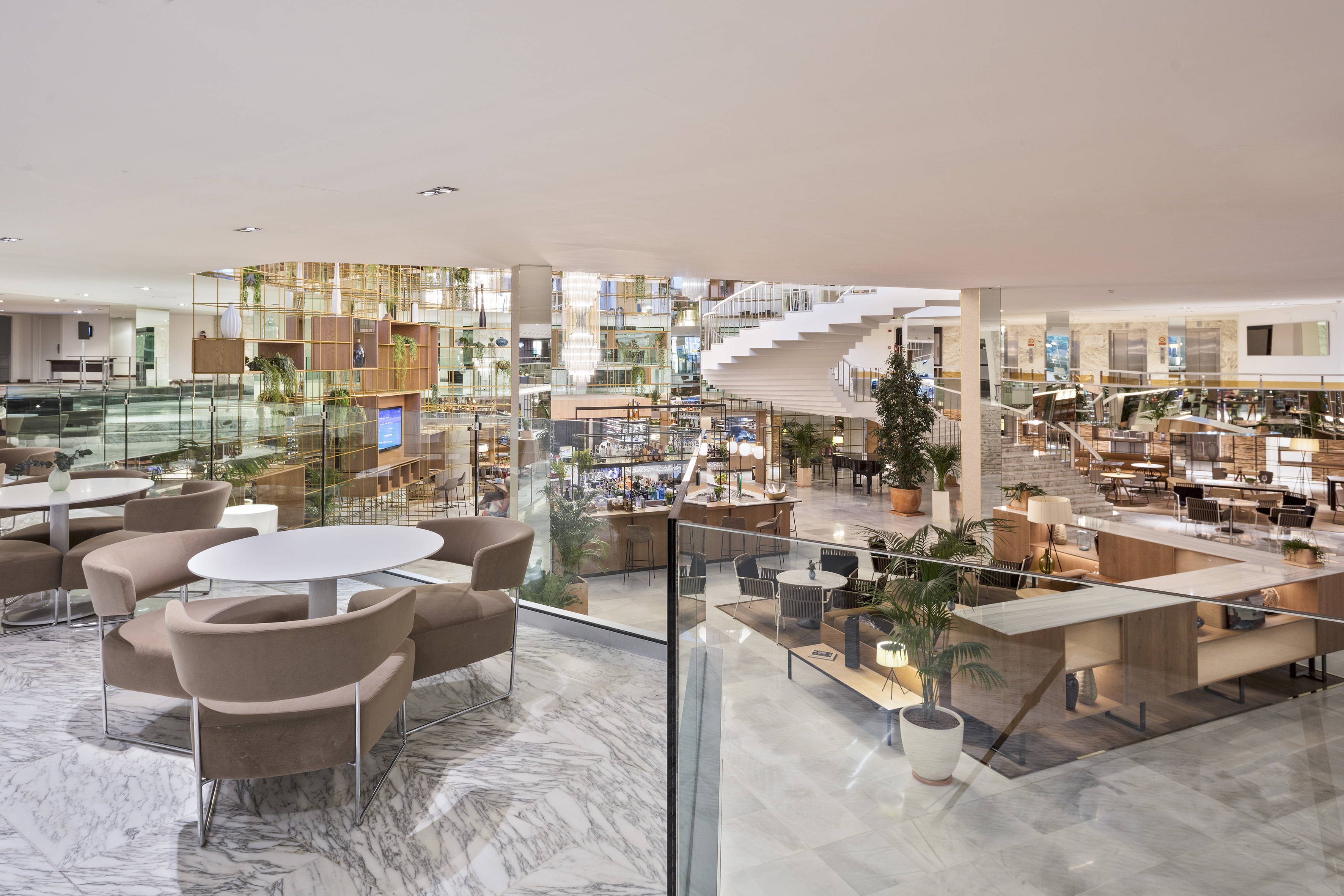 Modern hotel lobby lounge, marble floors, spiral staircase, and seating areas.