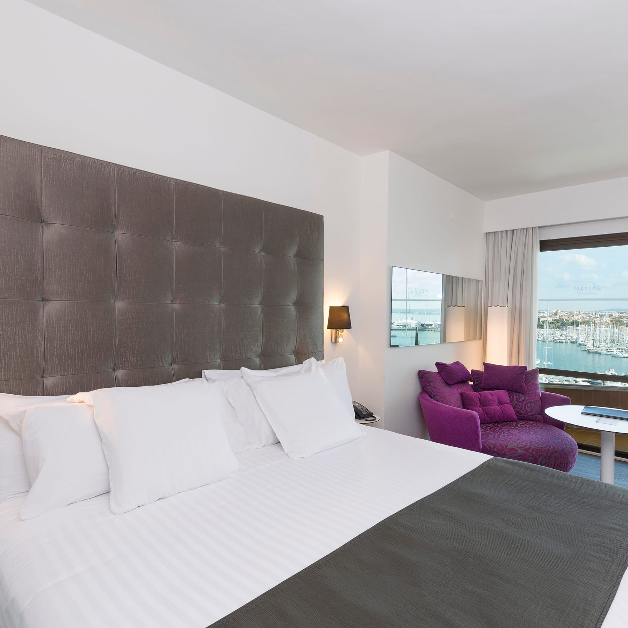 a large bed with a purple chair and a purple chair