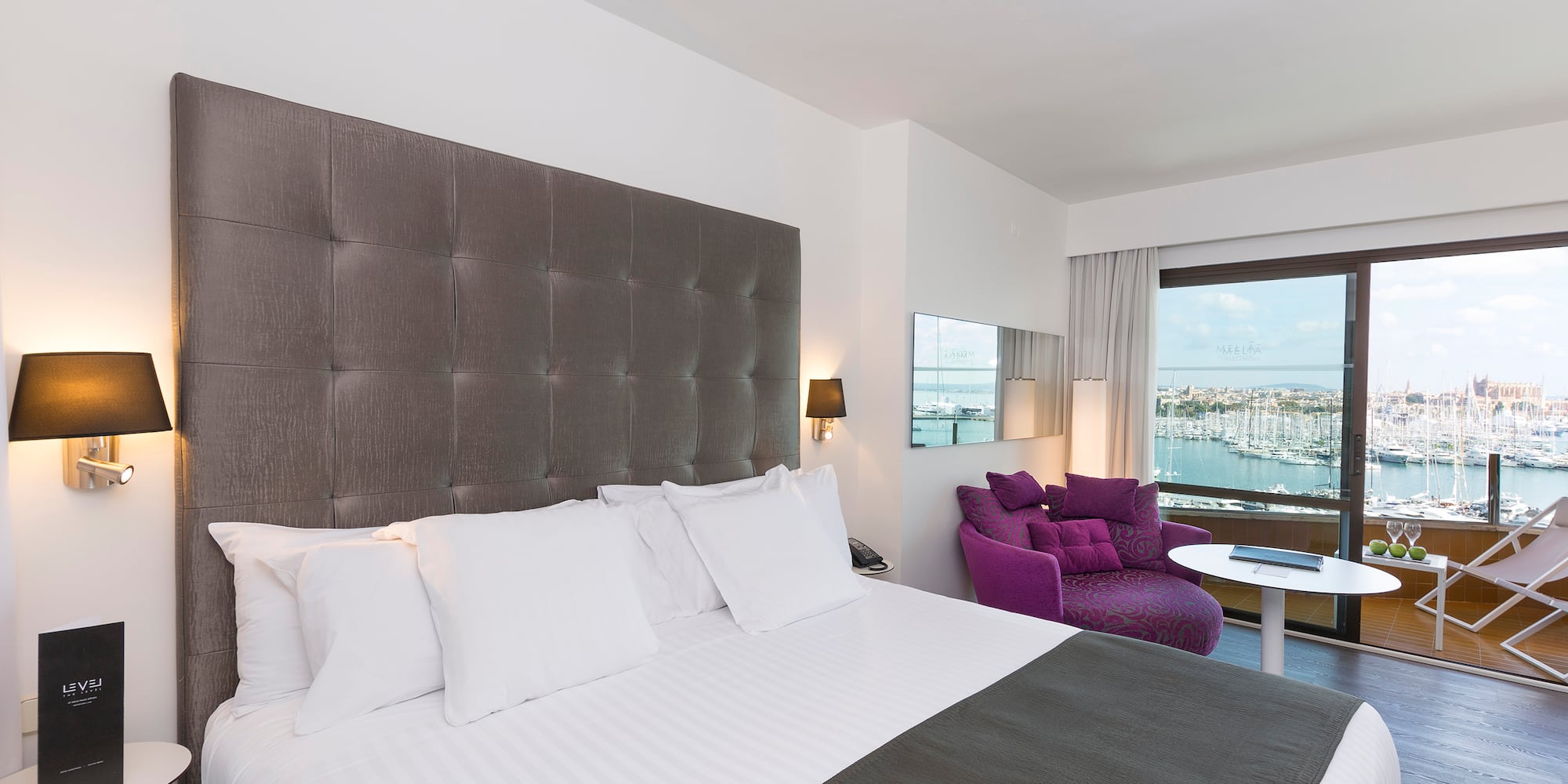 a large bed with a purple chair and a purple chair