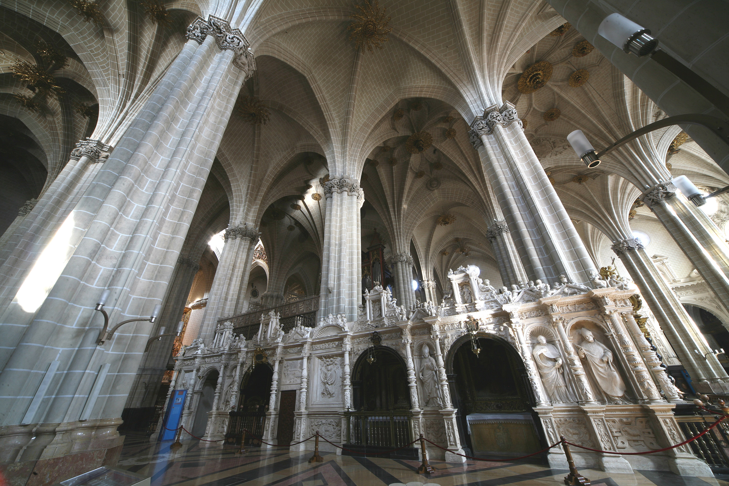 Ornate Gothic cathedral interior with vaulted ceilings, stone columns, carved screen.