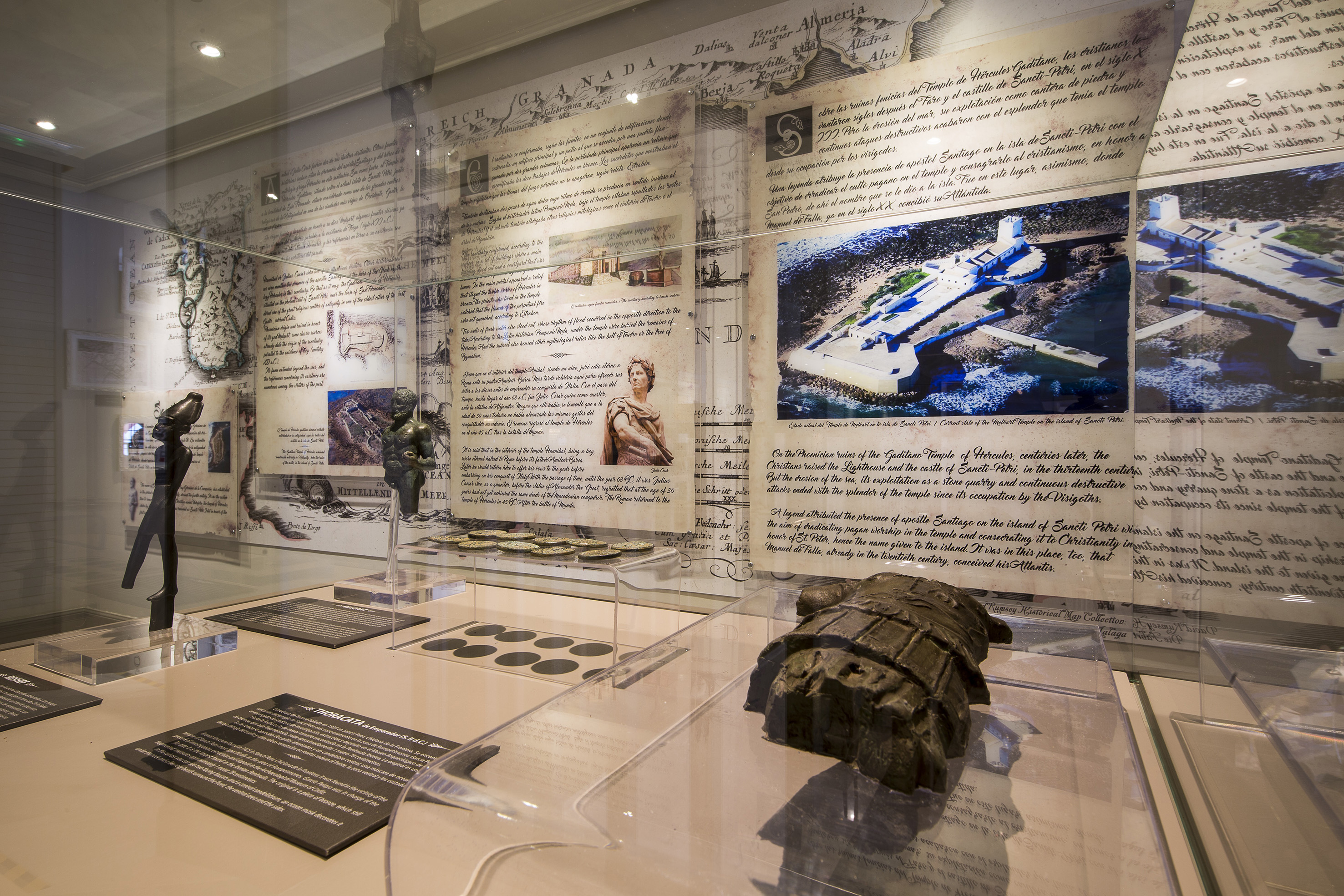 Archaeology exhibit with ancient maps, fortress, statues, coins, and Thoracata armor.