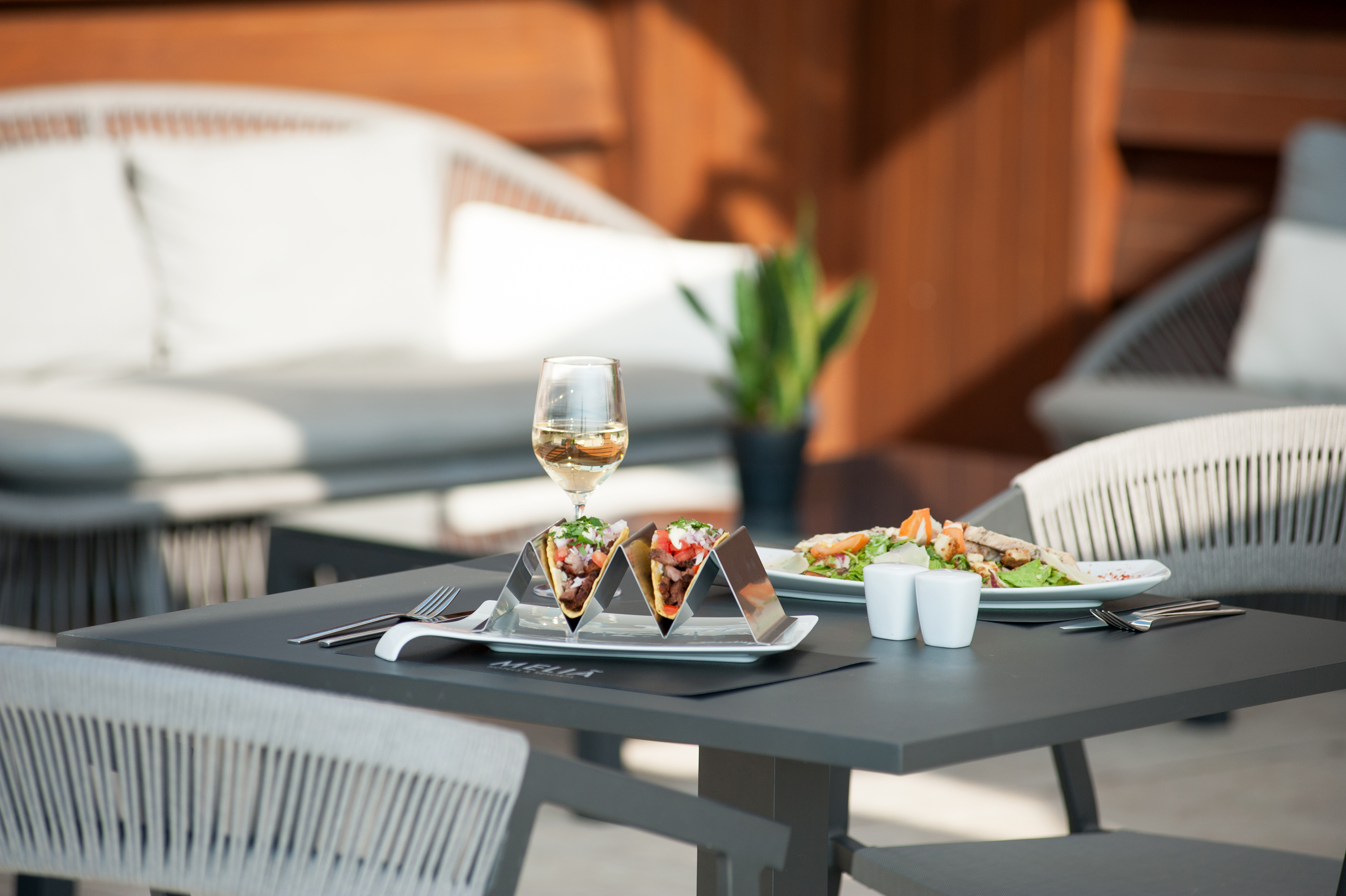 Tacos, white wine, and salad on an outdoor restaurant table.
