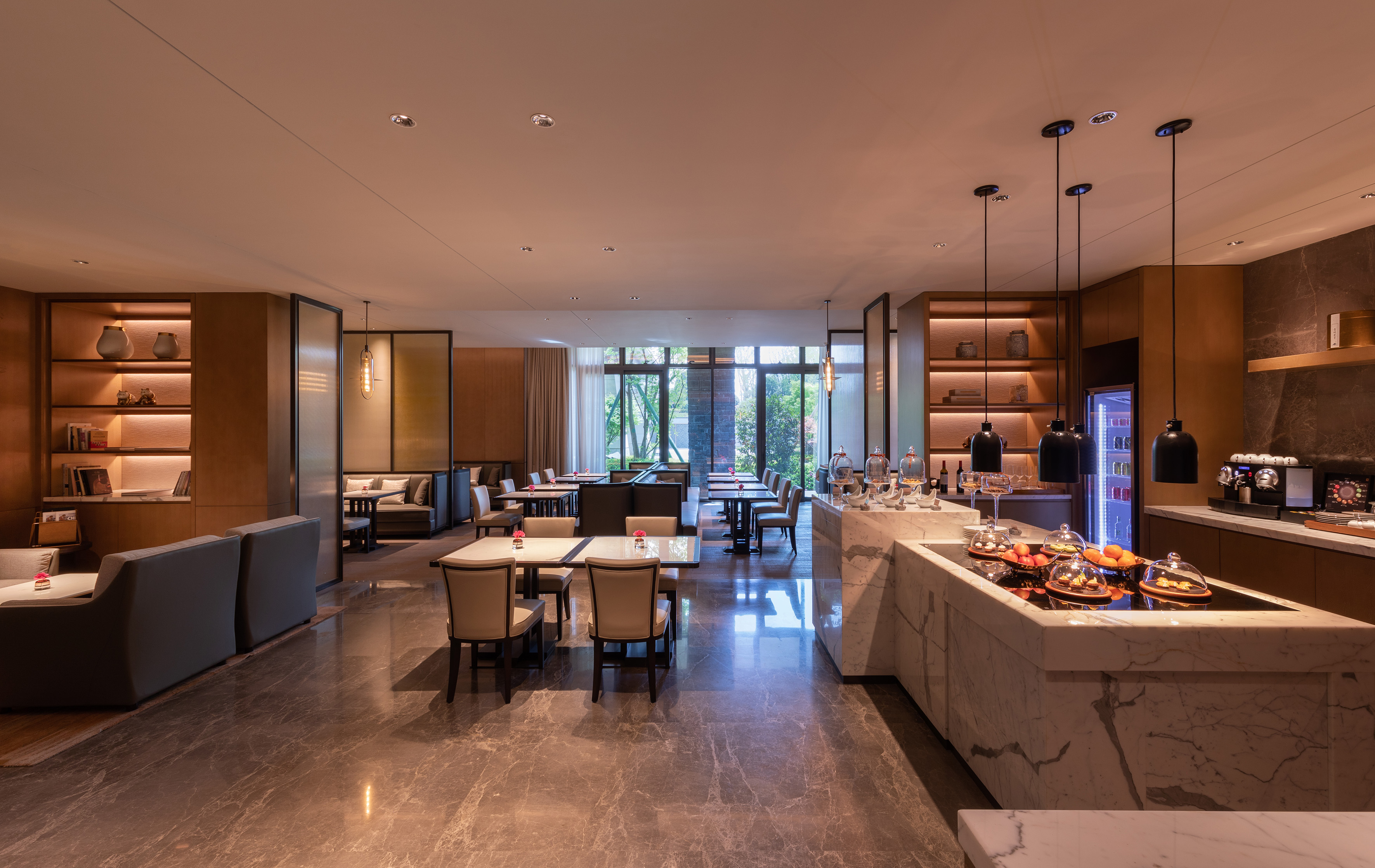 Elegant modern restaurant dining room with marble buffet and garden views.