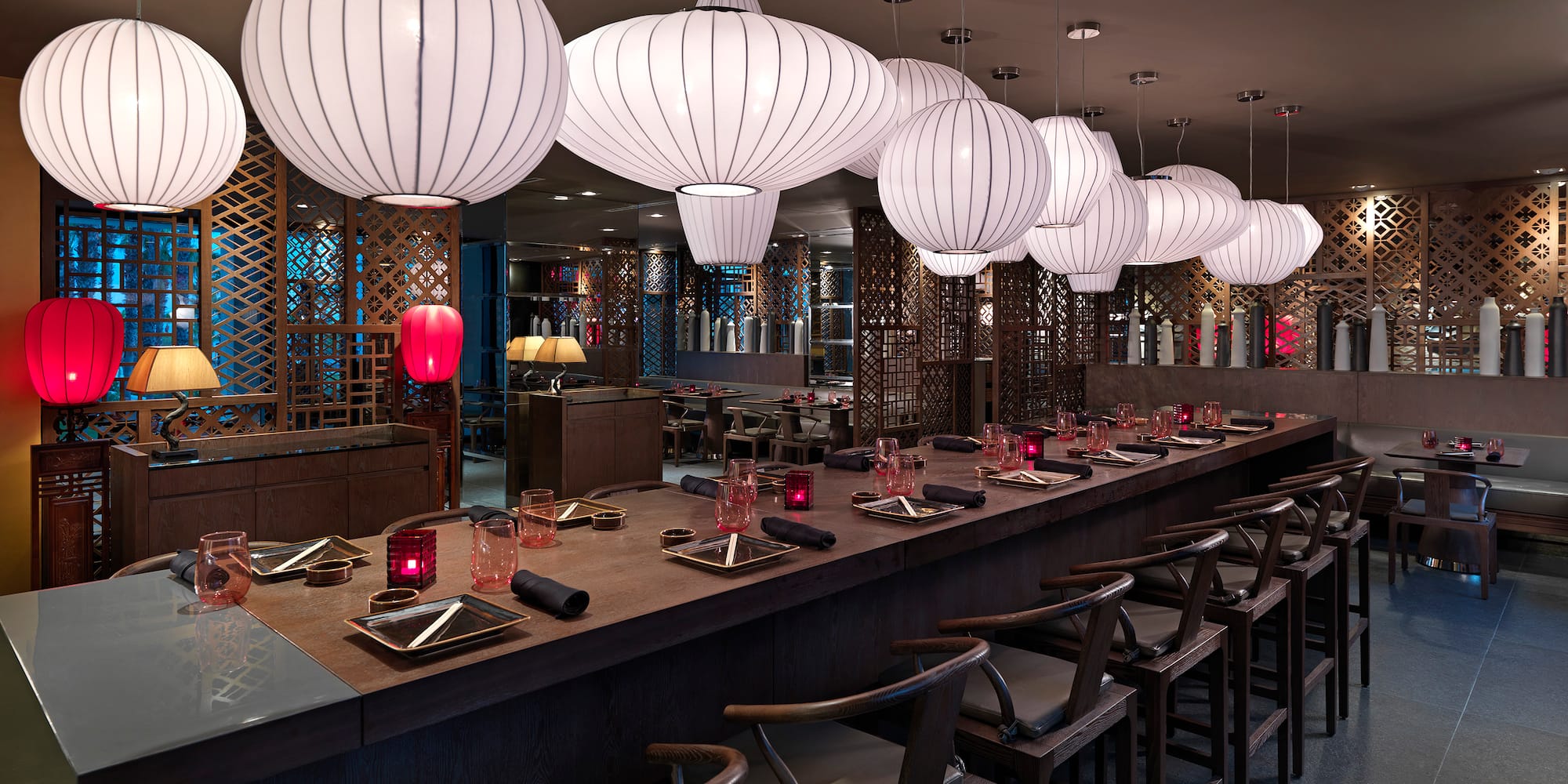 a long table with white lanterns from the ceiling