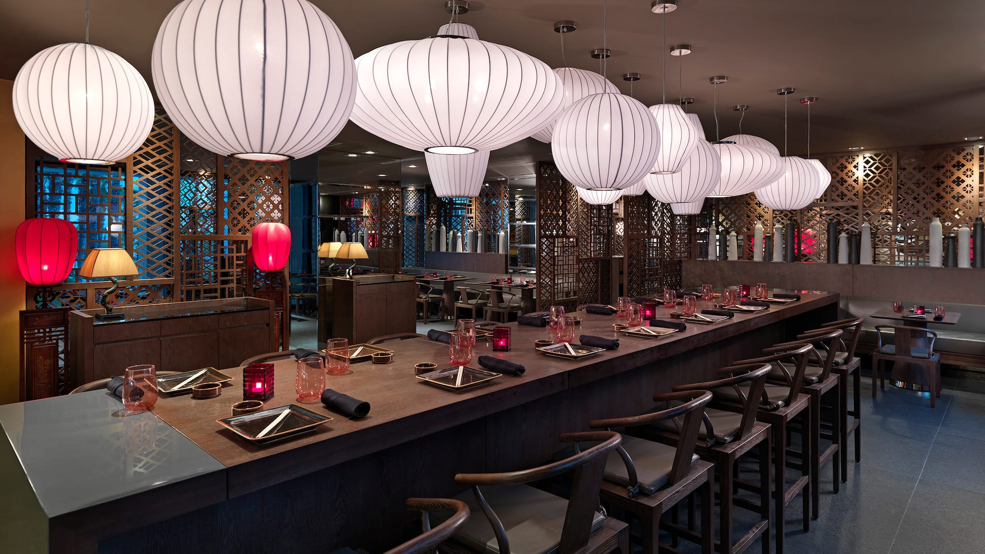 a long table with white lanterns from the ceiling