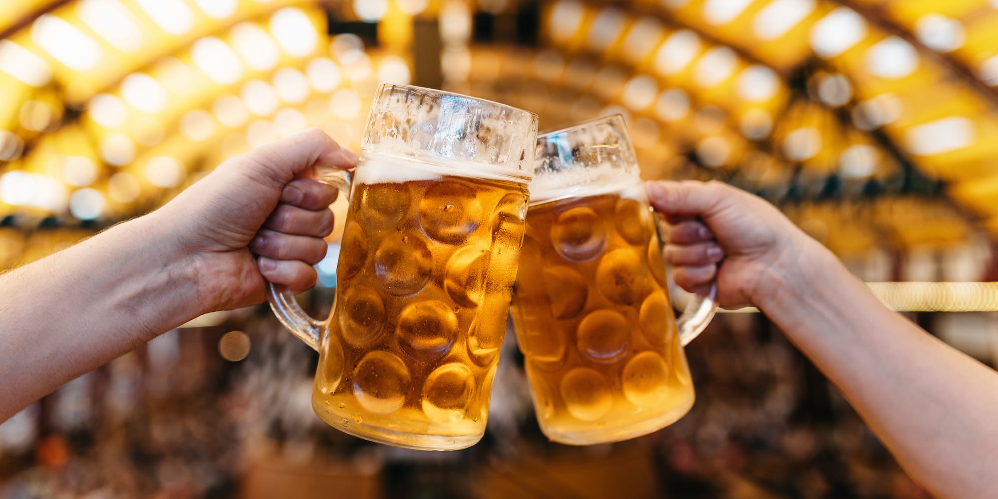 Brindis con dos jarras de cerveza en festival, estilo Oktoberfest.