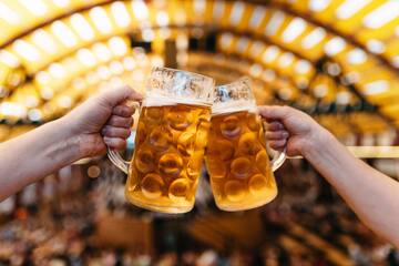 a pair of hands clinking glasses of beer