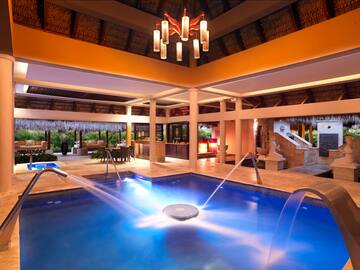 a pool with water jets in a room with a ceiling and a chandelier
