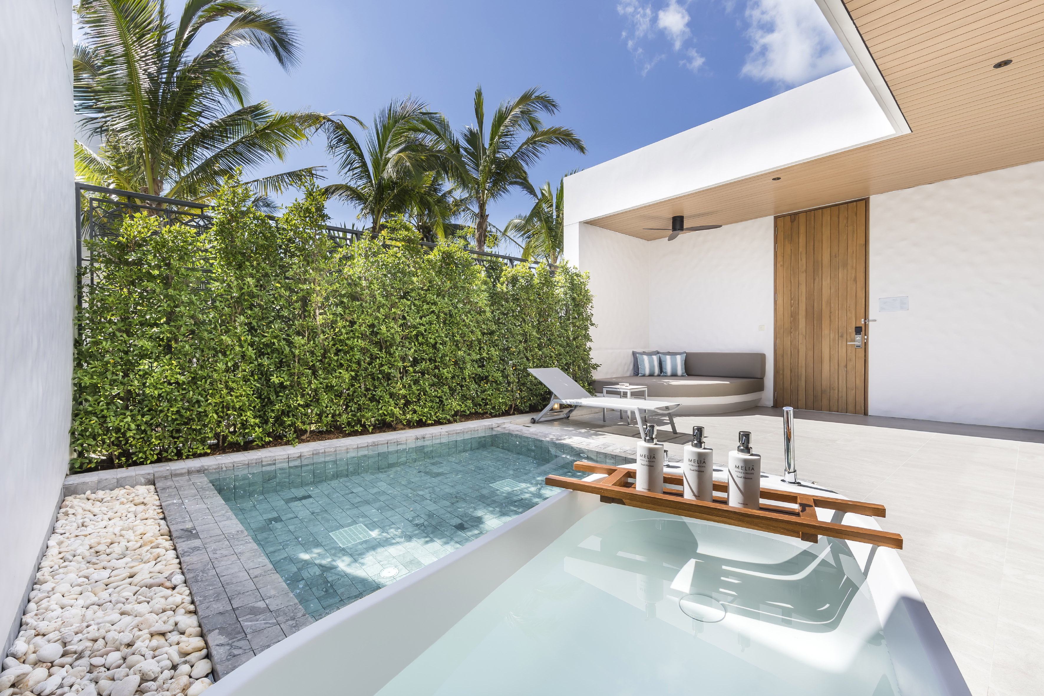 Tropical private pool terrace with outdoor bath and lounge area.