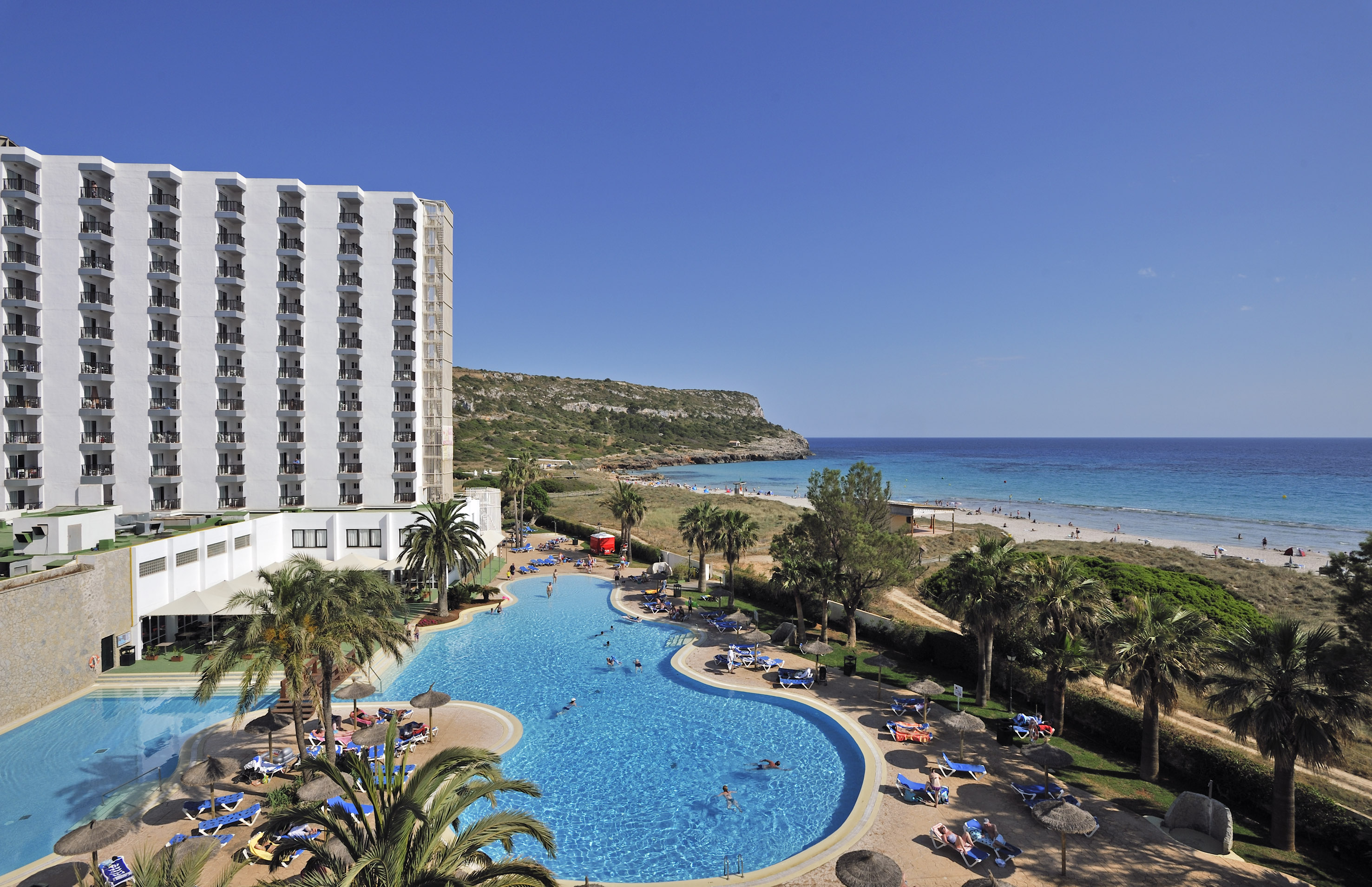 a swimming pool with palm trees and a building by it