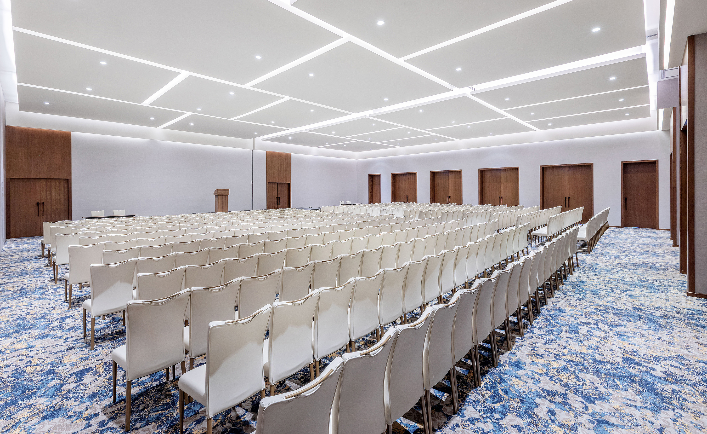 Empty modern conference room with white chairs and blue patterned carpet.