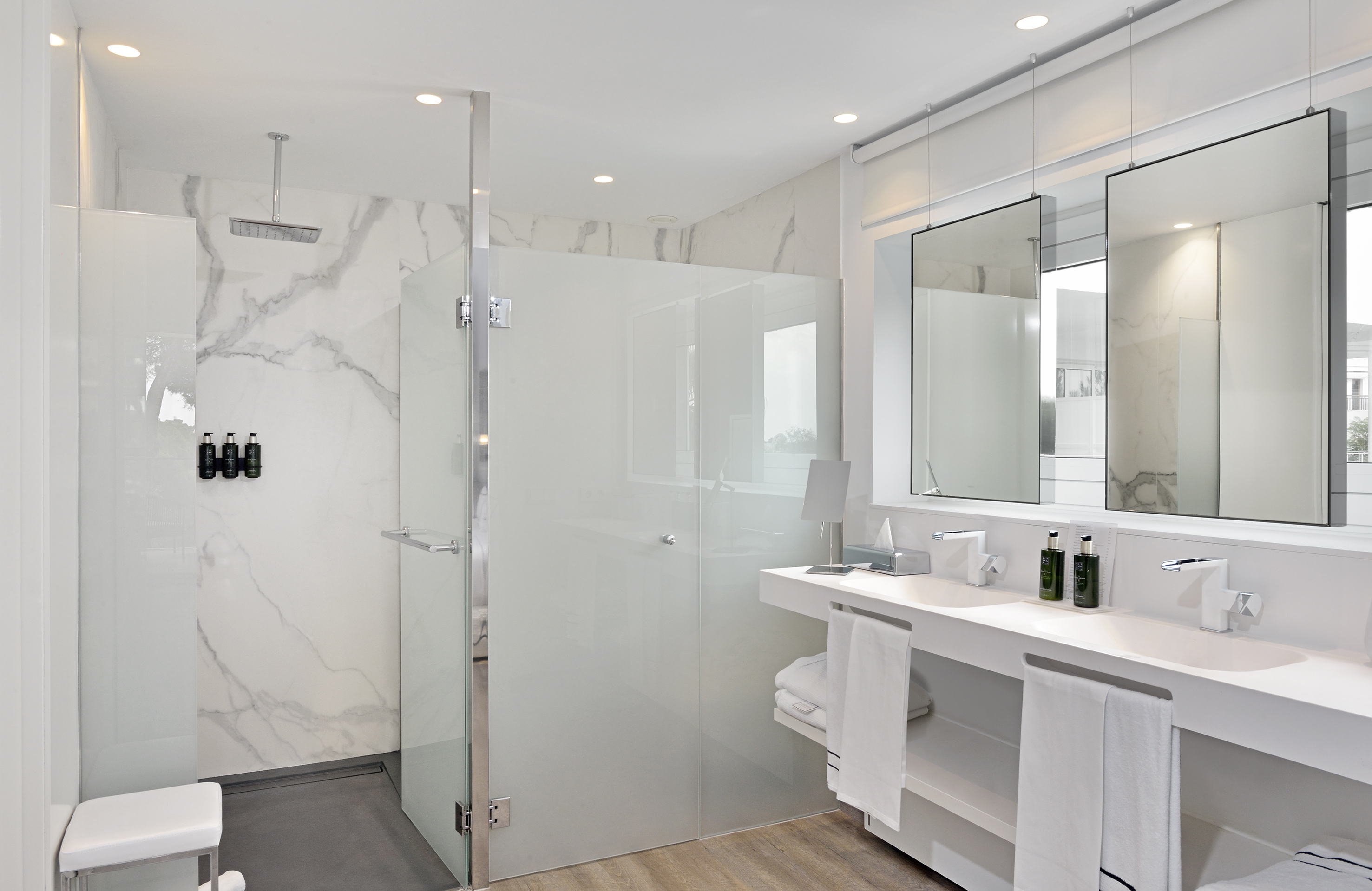 Modern bathroom with marble shower, double vanity, and floating mirrors.