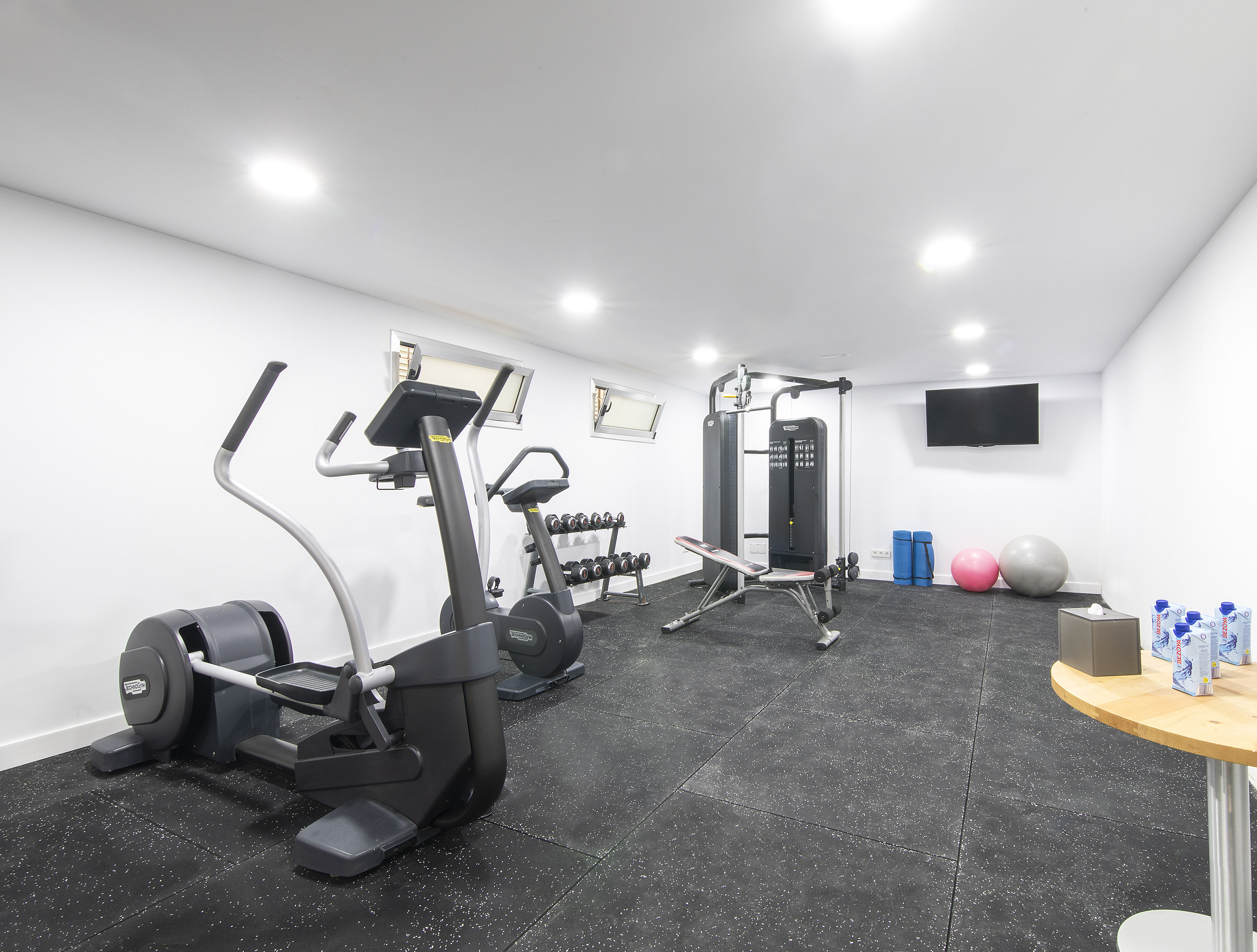 Private gym with cardio and weight training equipment, rubber floor.