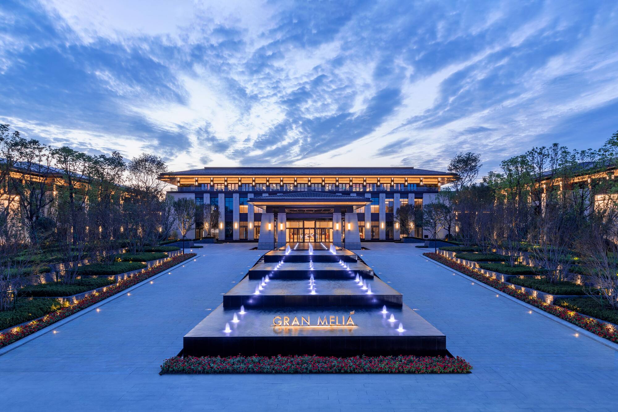 Gran Melia hotel entrance at dusk with lit fountain and modern architecture.