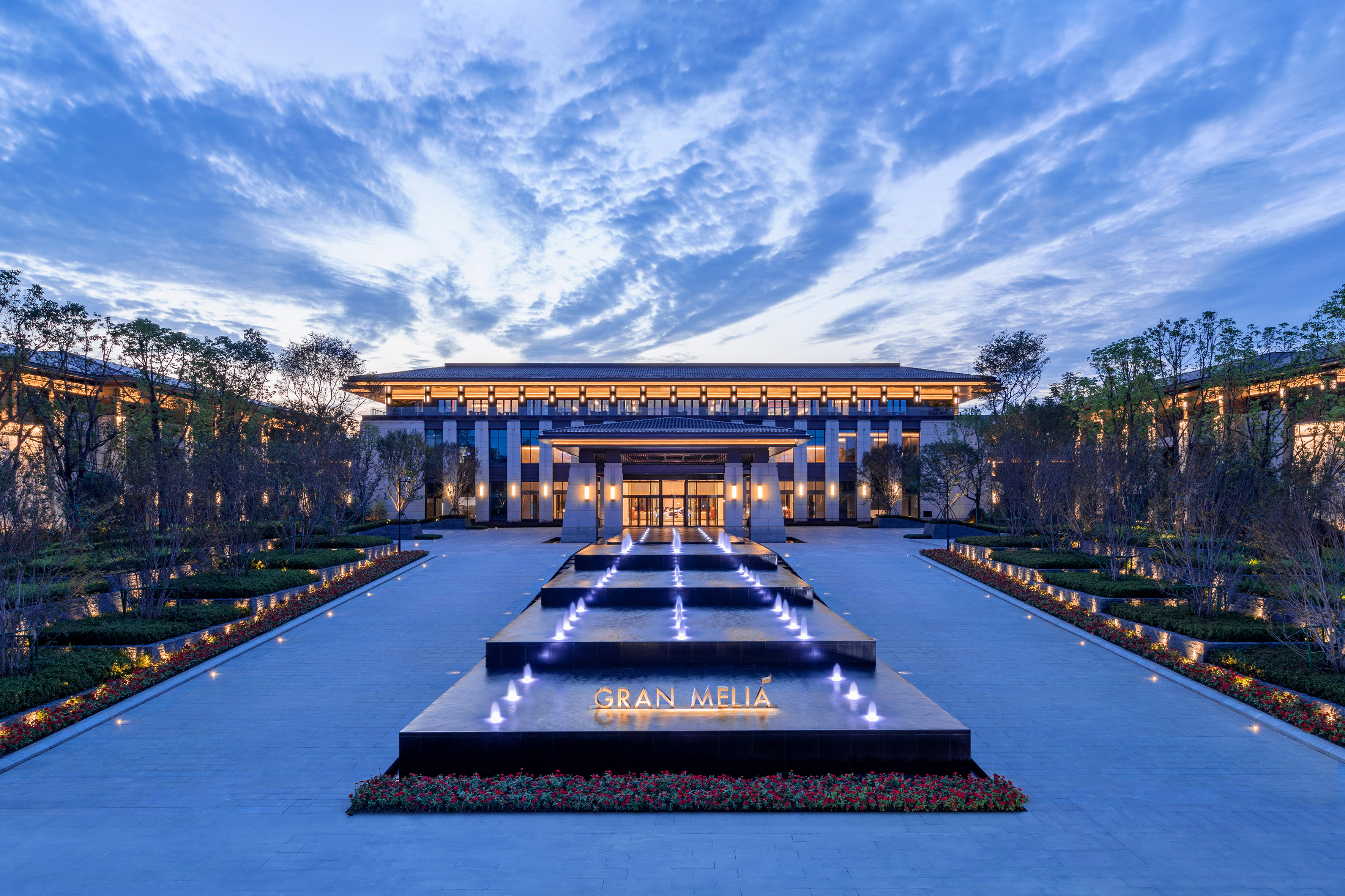 Gran Melia hotel entrance at dusk with lit fountain and modern architecture.