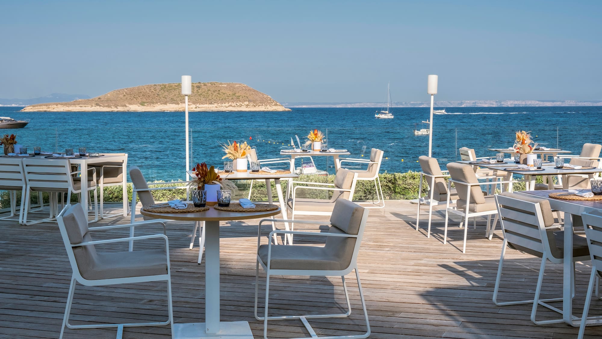 a table and chairs on a deck with a body of water in the background