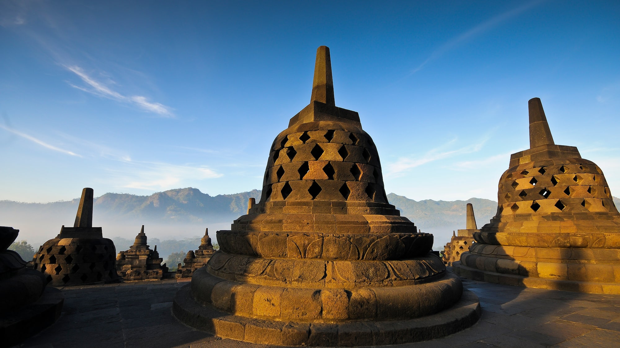 a stone structure with Borobudur in the background