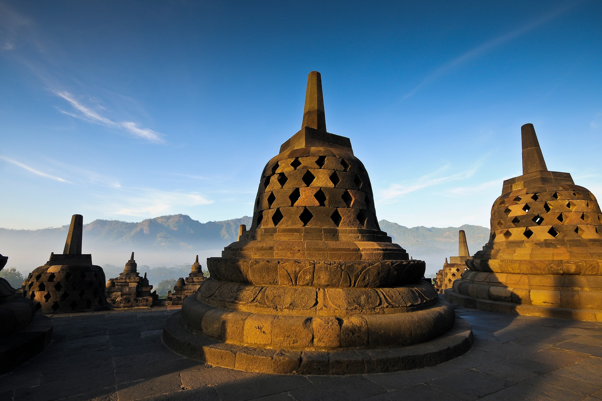 a stone structure with Borobudur in the background