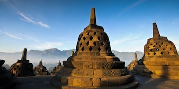 a stone structure with Borobudur in the background