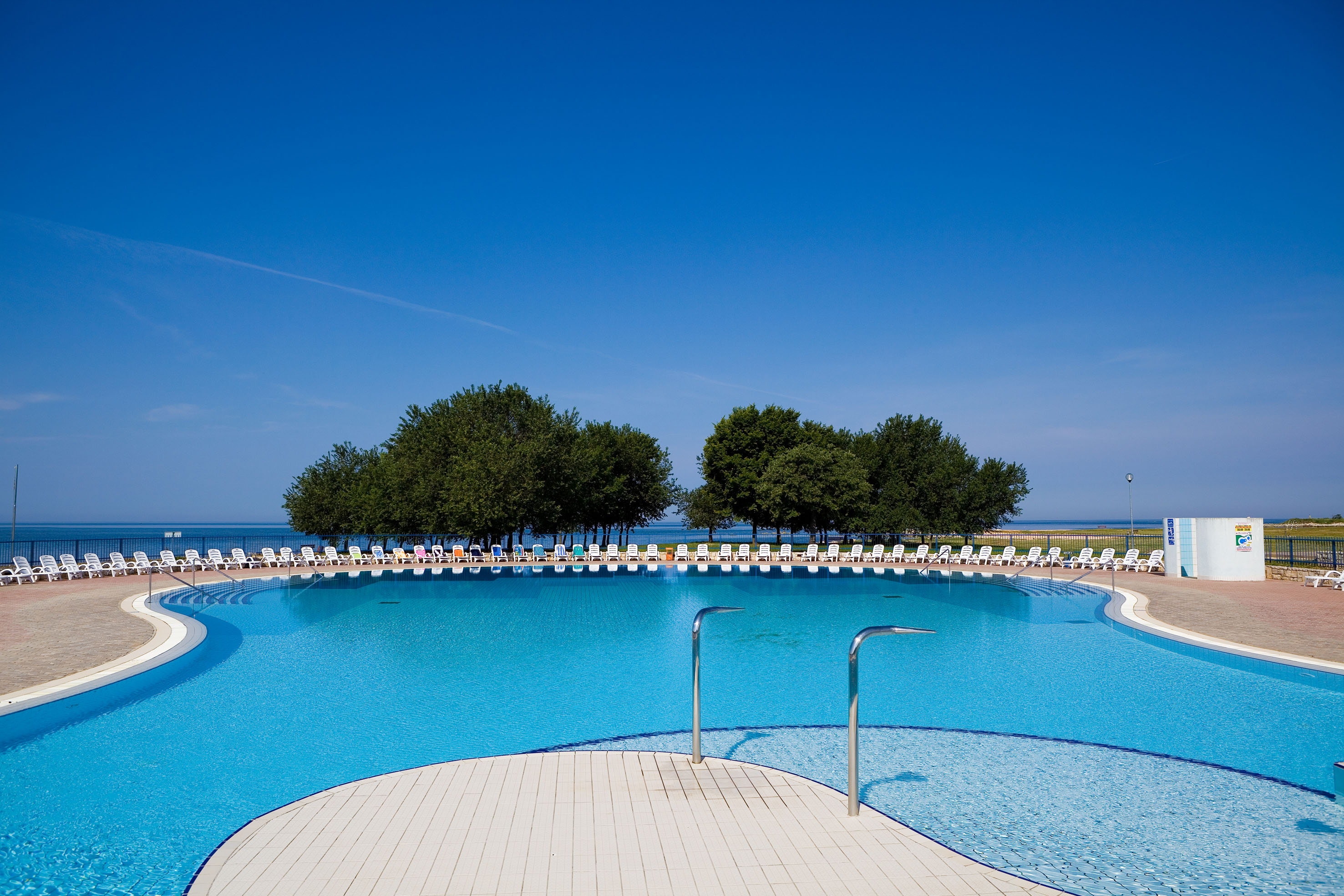a pool with chairs and trees in the background