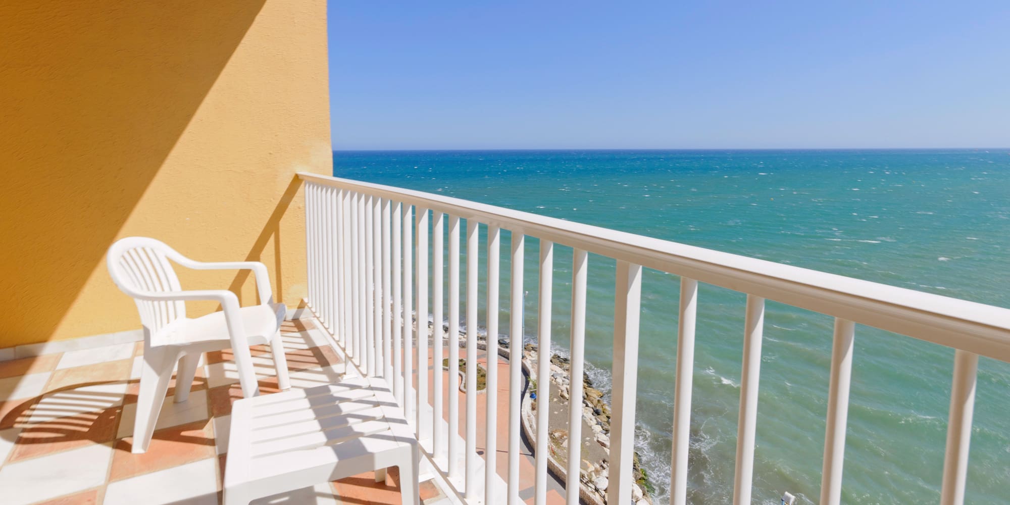 a balcony with chairs and a body of water