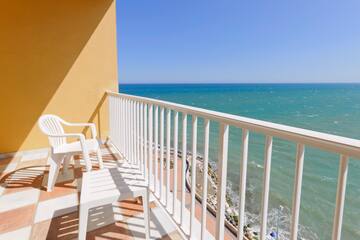 a balcony with chairs and a body of water