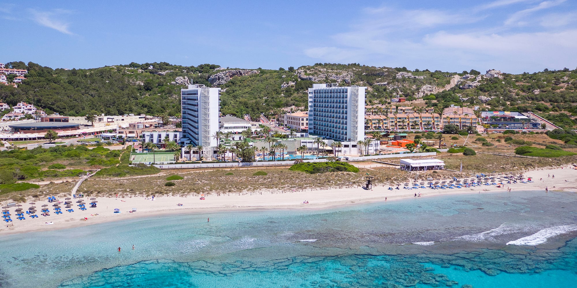 a beach with buildings and blue water