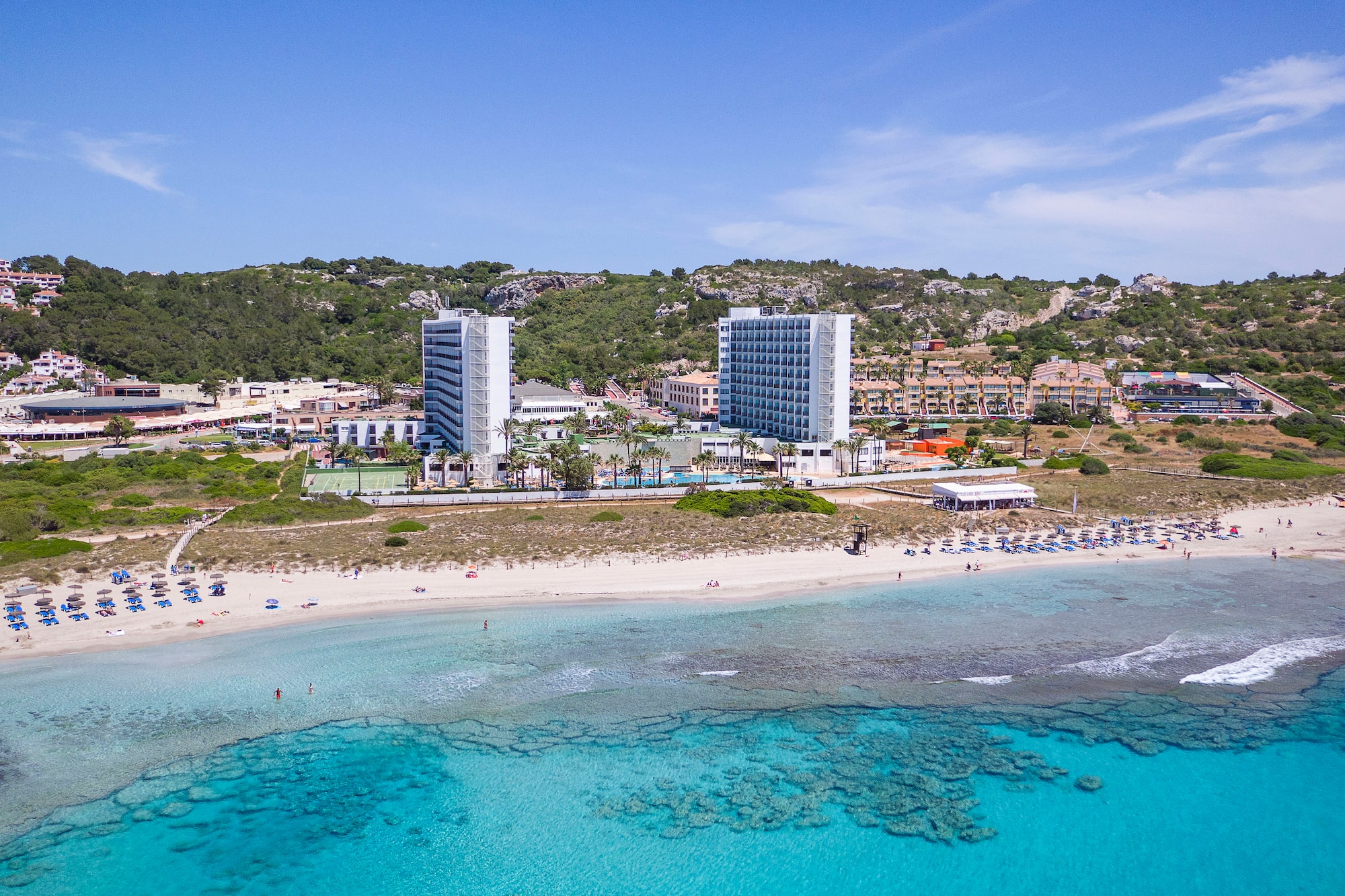 a beach with buildings and blue water