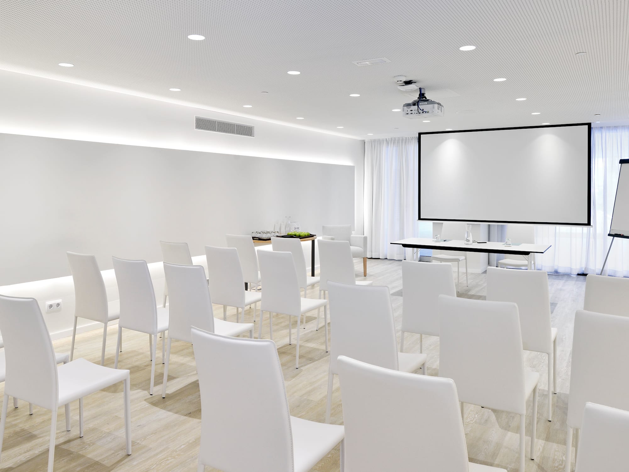 a room with white chairs and a projector screen