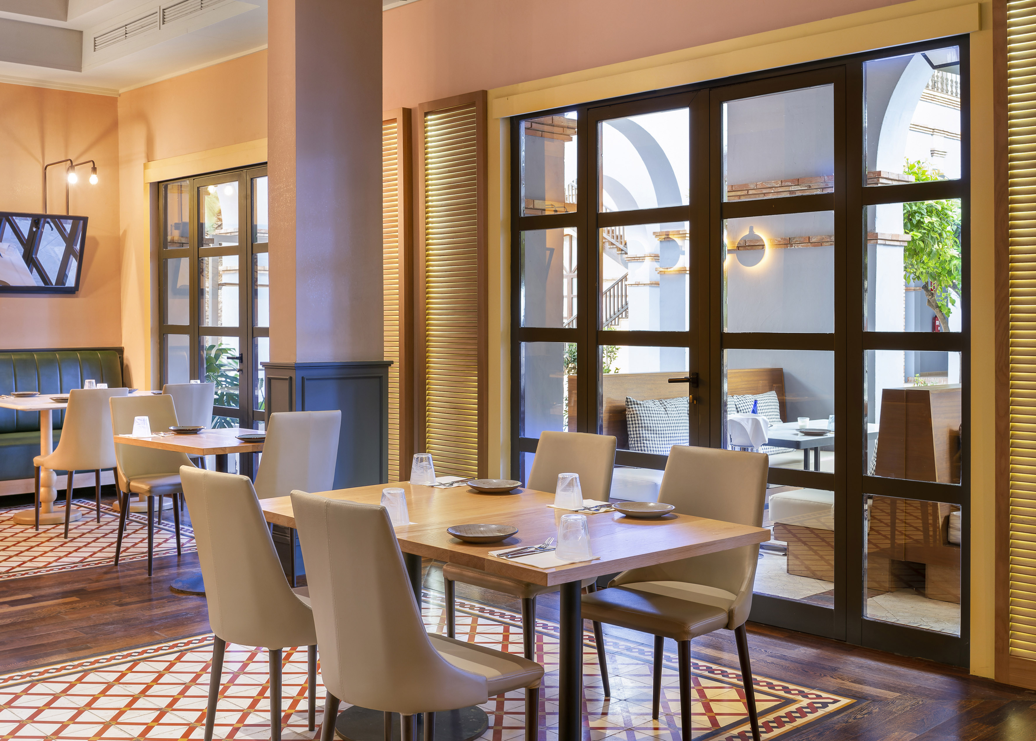 Elegant restaurant interior with patterned floor, wooden tables, and outdoor terrace.