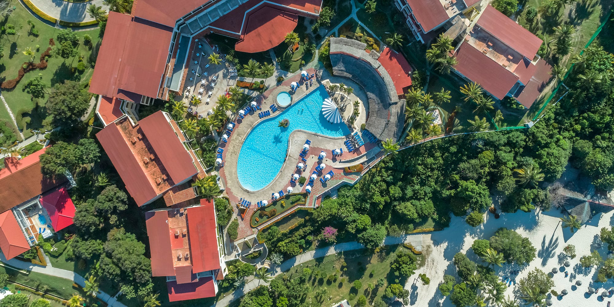 an aerial view of a resort with a pool and buildings