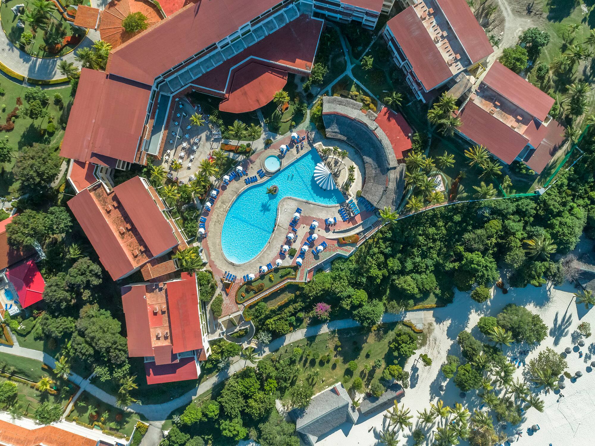 an aerial view of a resort with a pool and buildings