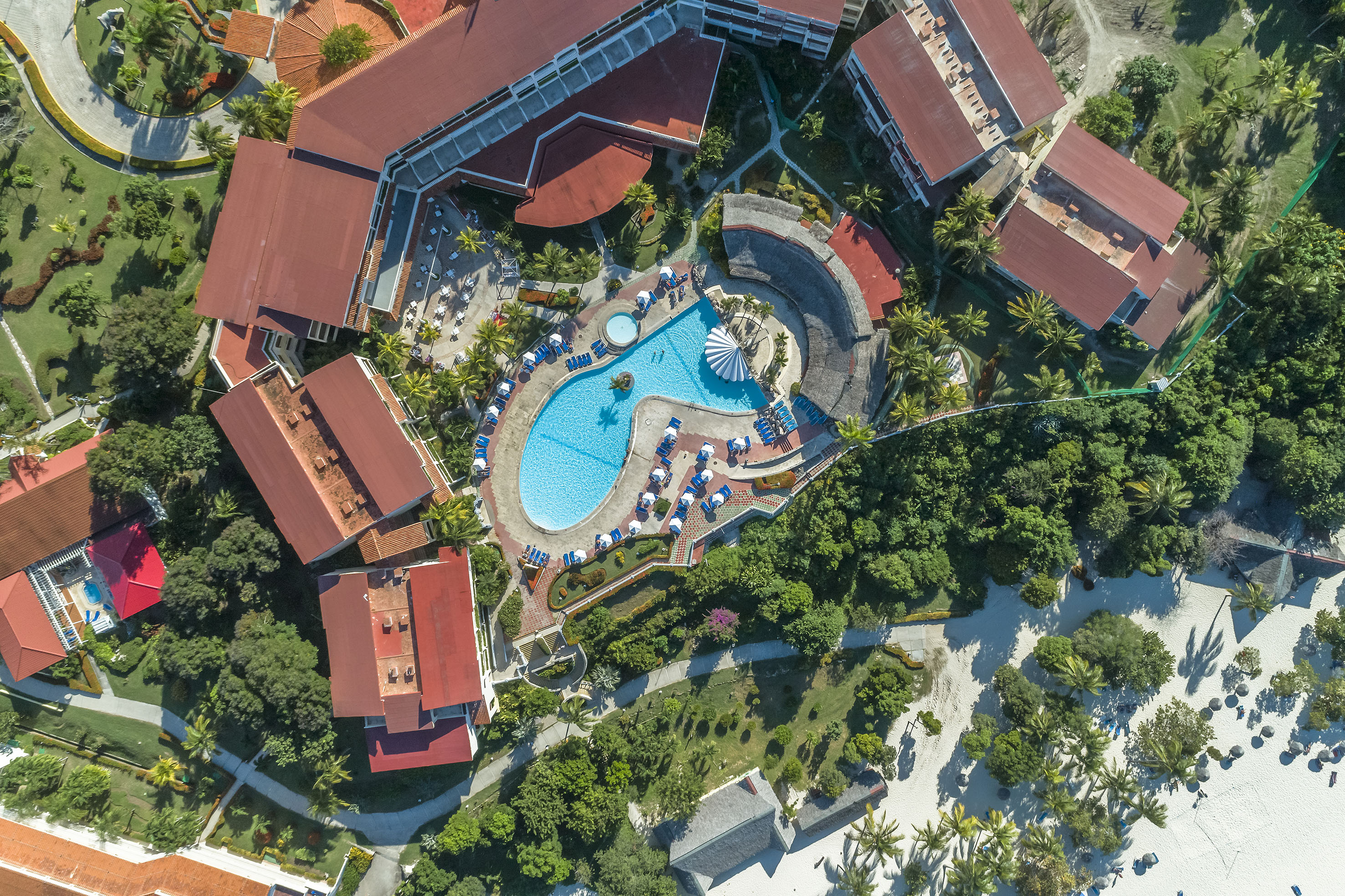 an aerial view of a resort with a pool and buildings