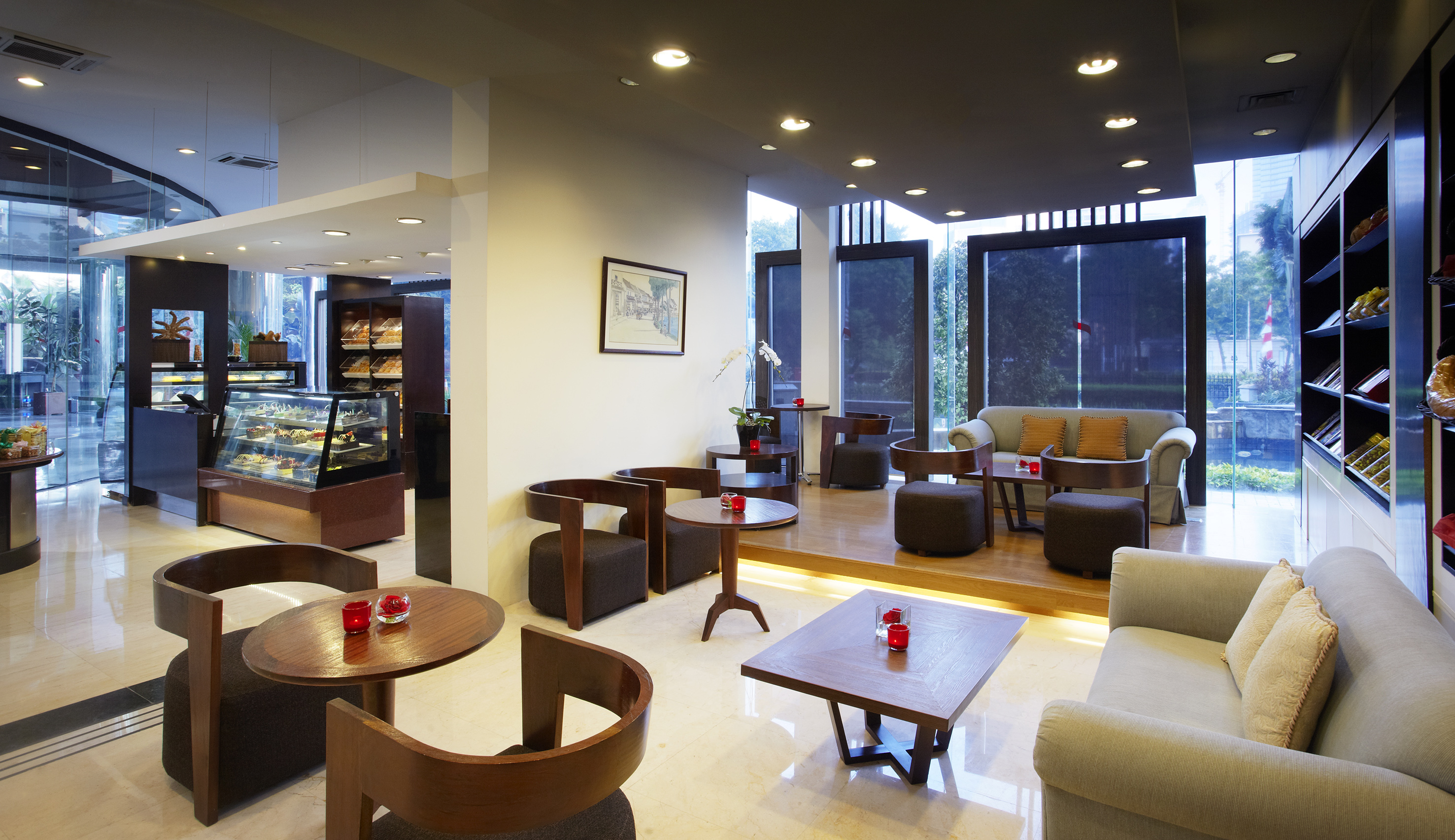 Modern cafe lounge with pastry display, tables, and outdoor window view.