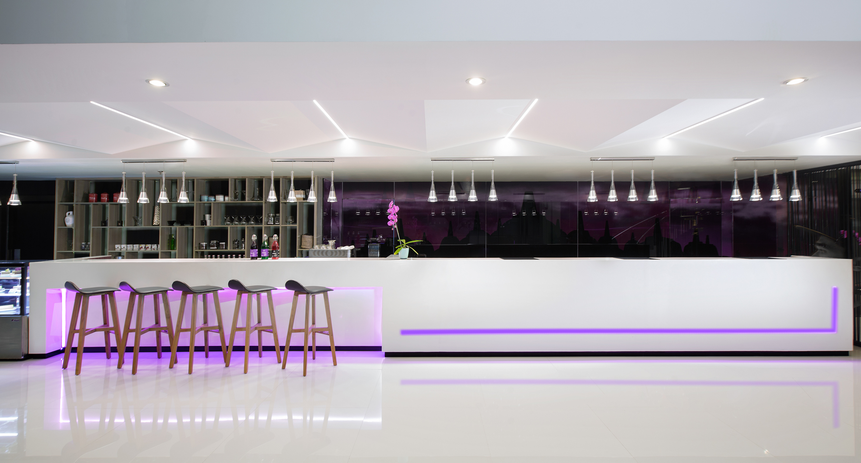 Modern white bar counter with purple LED lighting, bar stools, sleek interior.