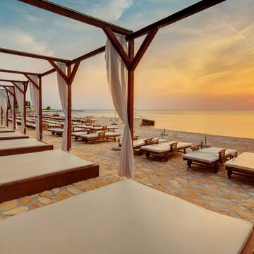 a beach with lounge chairs and a sunset