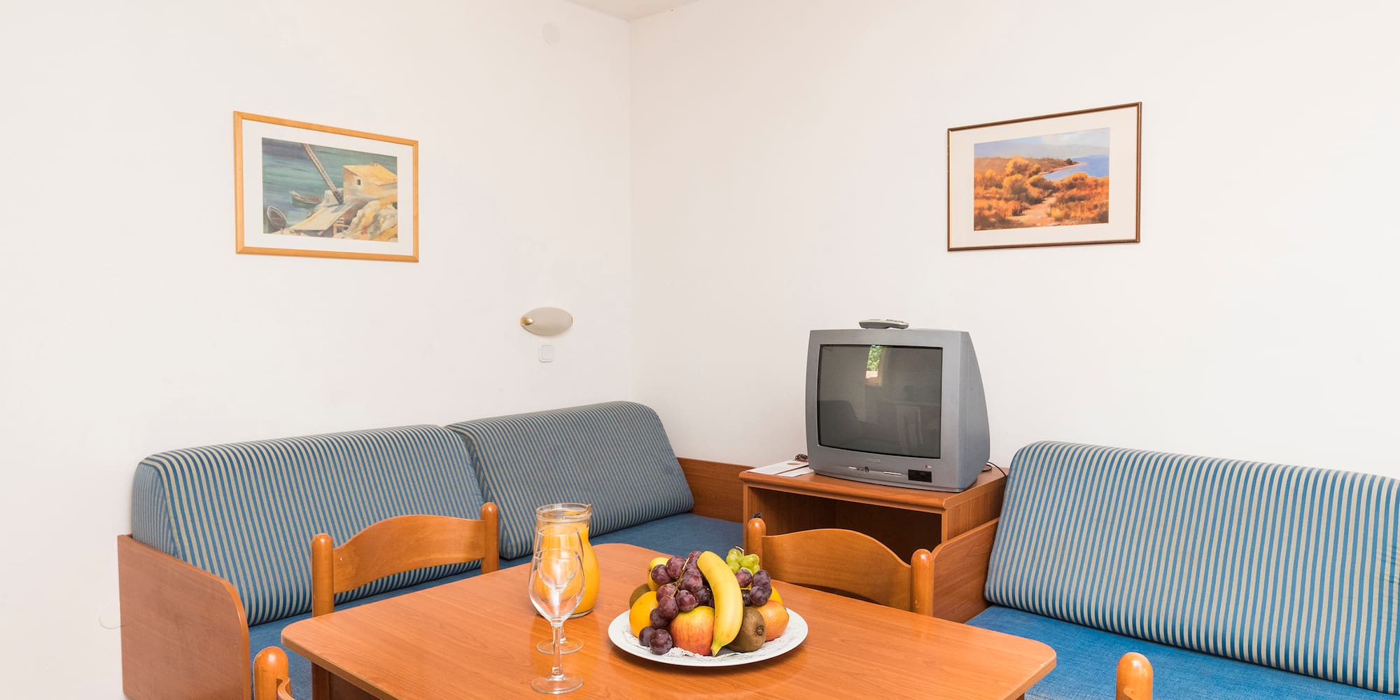 a room with a television and a table with fruit on it