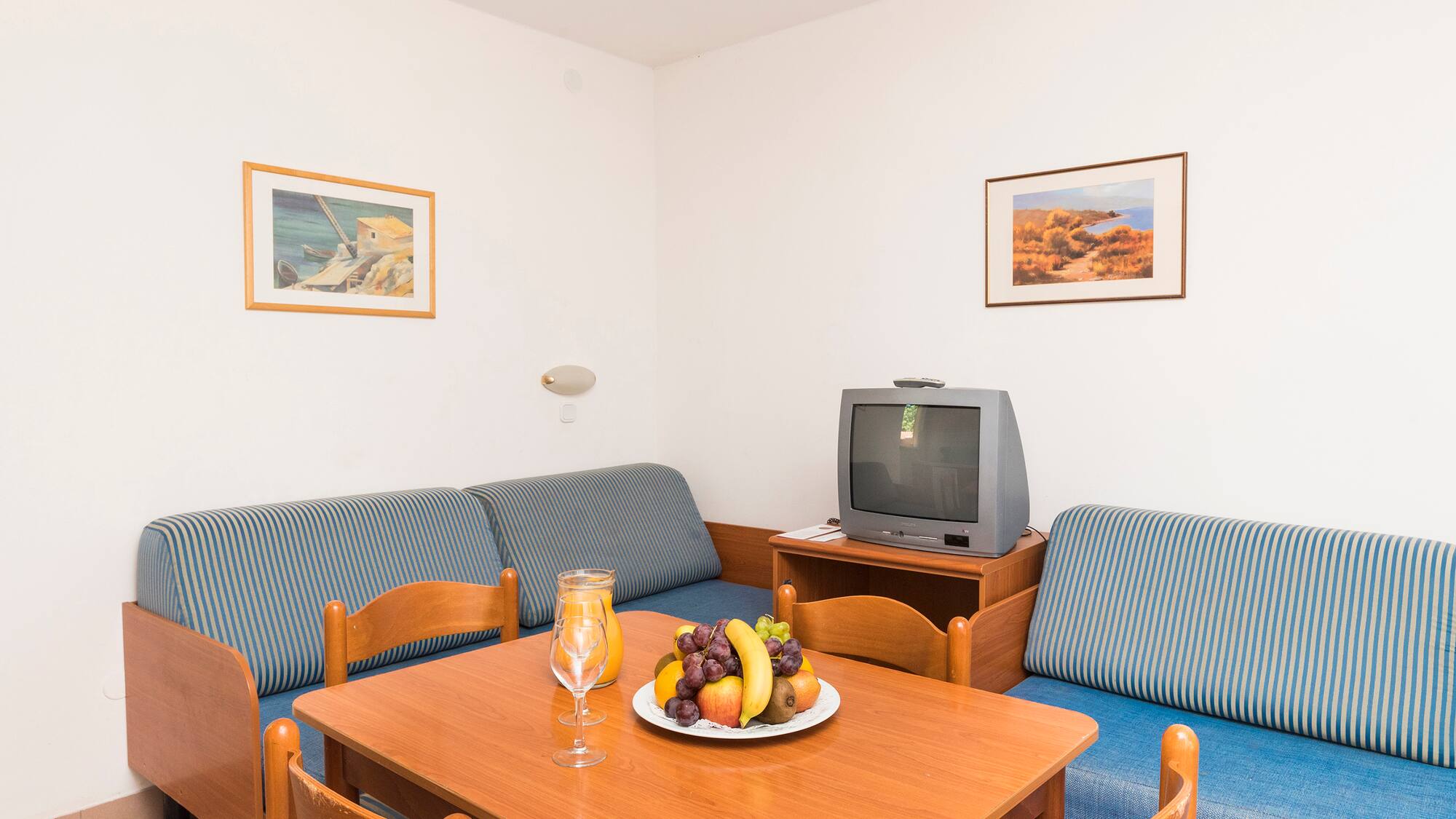 a room with a television and a table with fruit on it