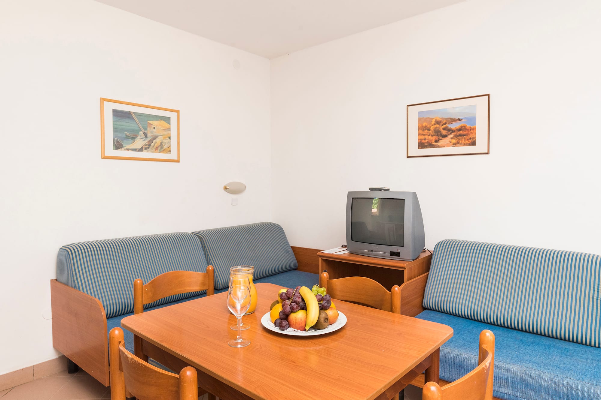 a room with a television and a table with fruit on it
