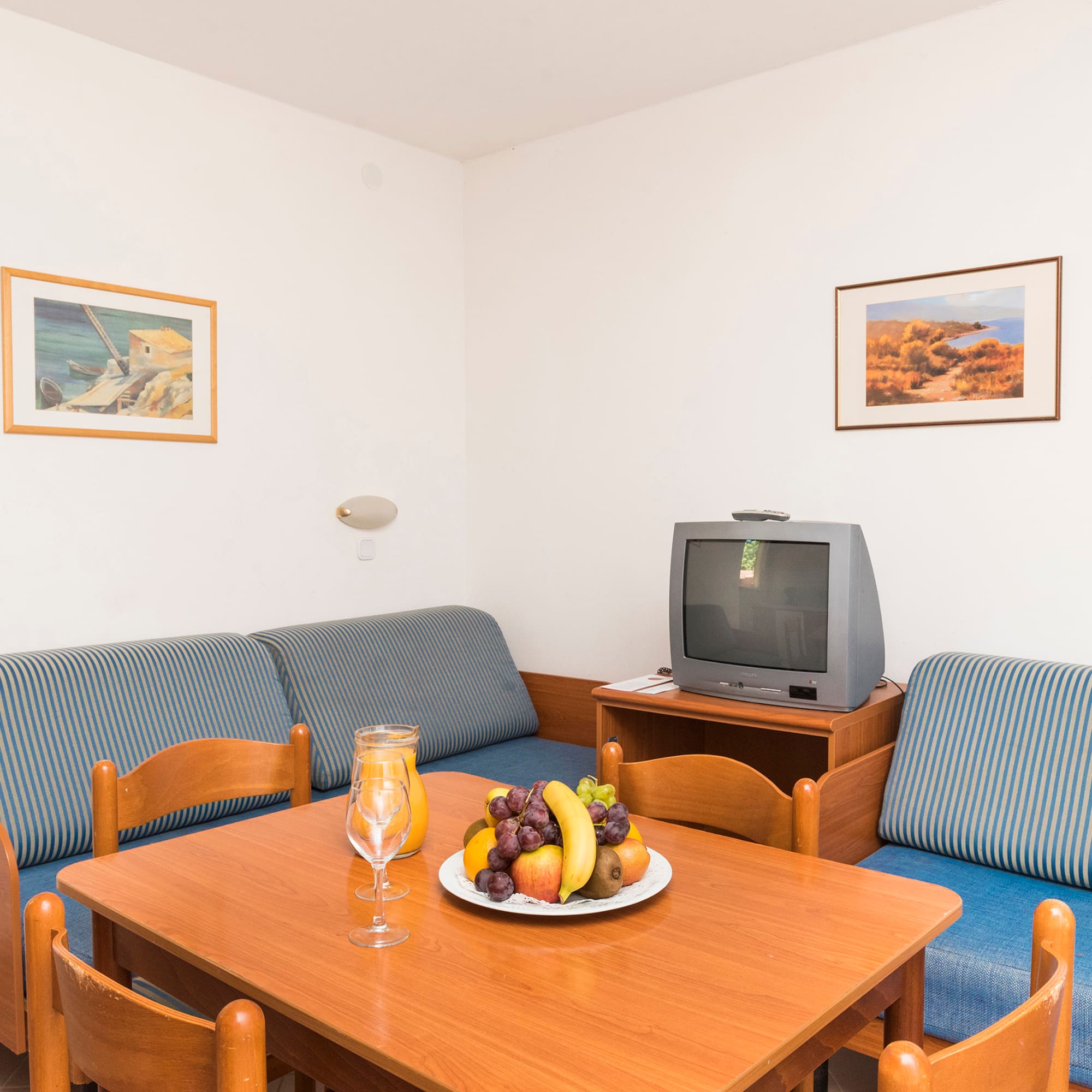 a room with a television and a table with fruit on it