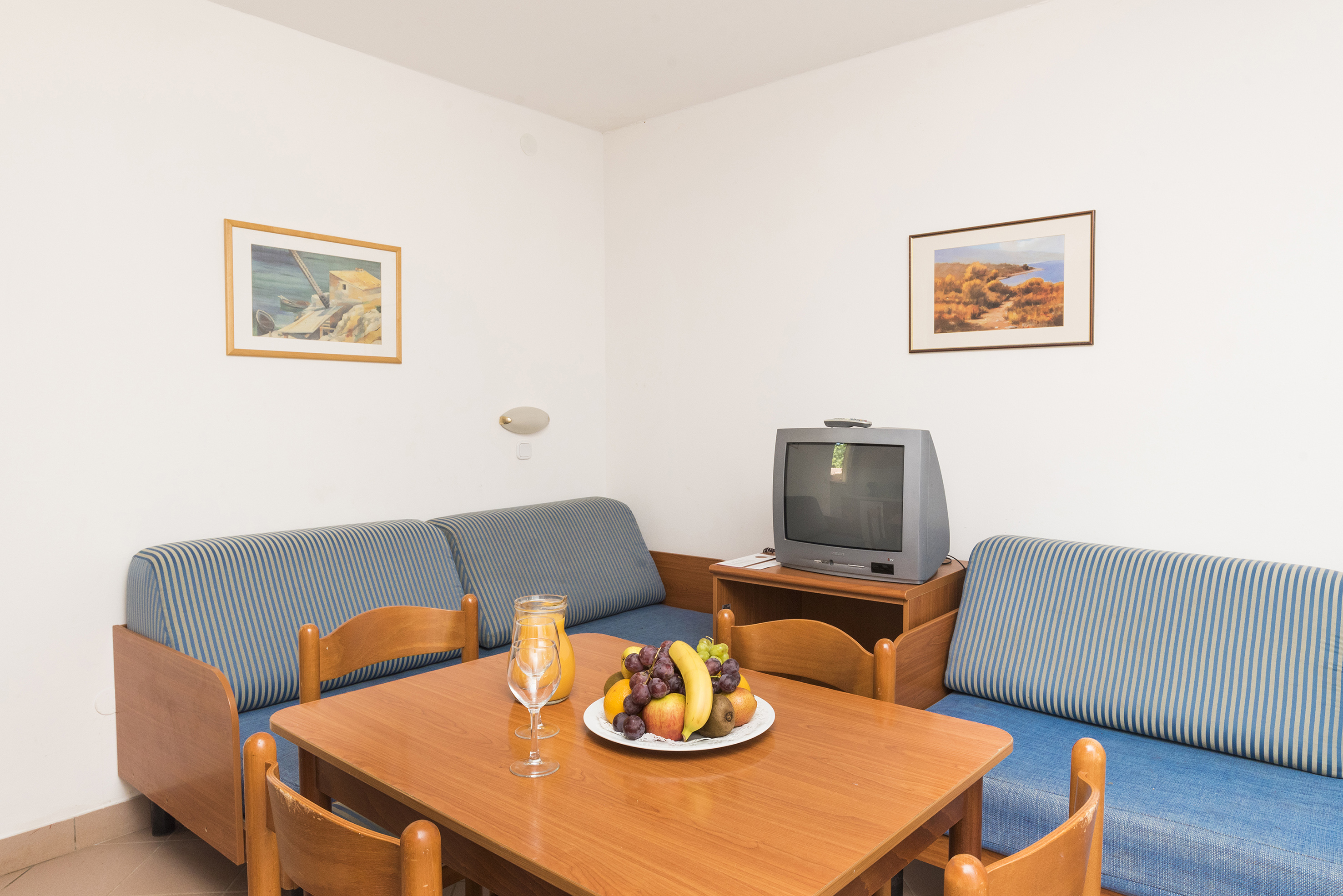 a room with a television and a table with fruit on it