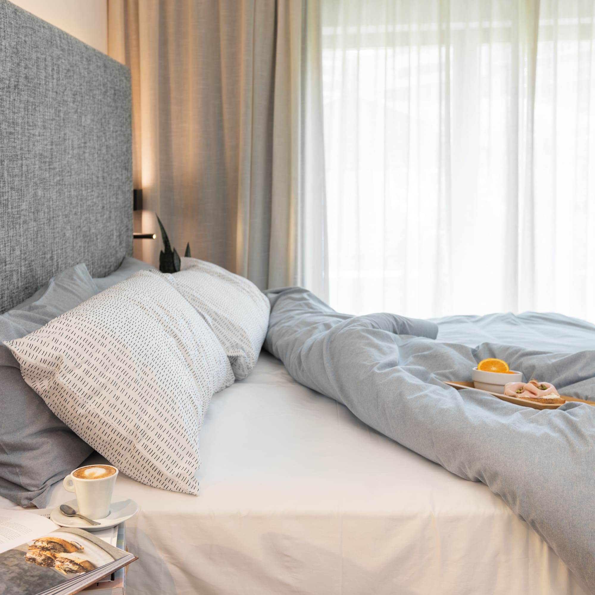 a bed with a tray of coffee and a plate of food